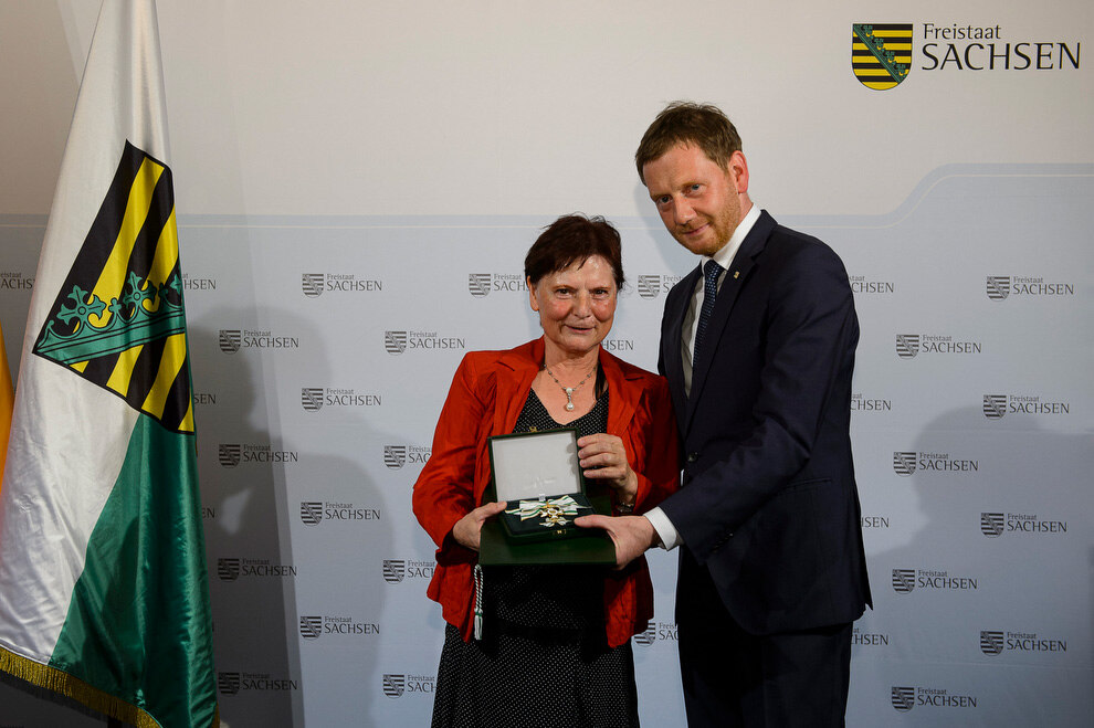 Eine Frau und ein Mann halten eine Medialle in der Hand.