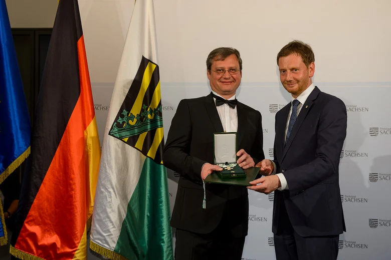 Zwei Männer haltne eine Medaille in der Hand.