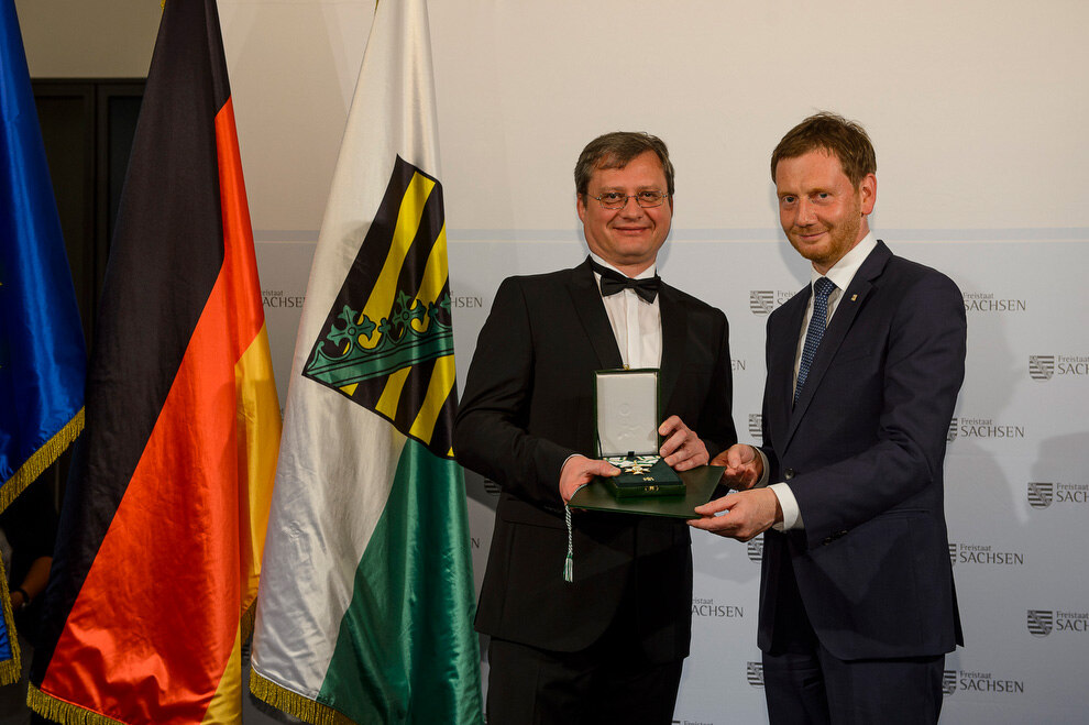 Zwei Männer haltne eine Medaille in der Hand.