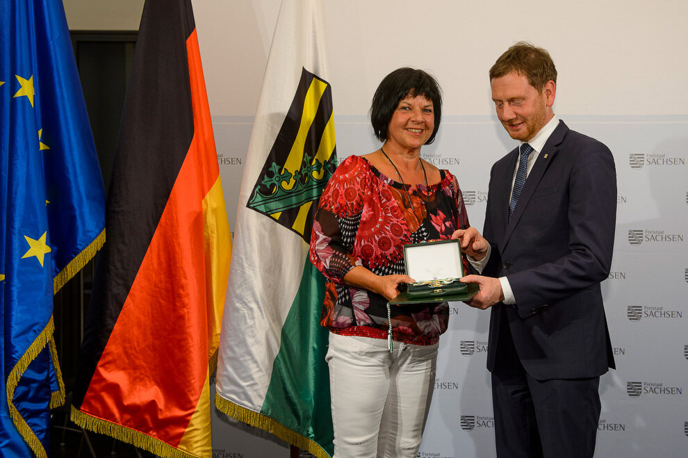 Ein Mann und eine Frau halten eine Medaille in der Hand.